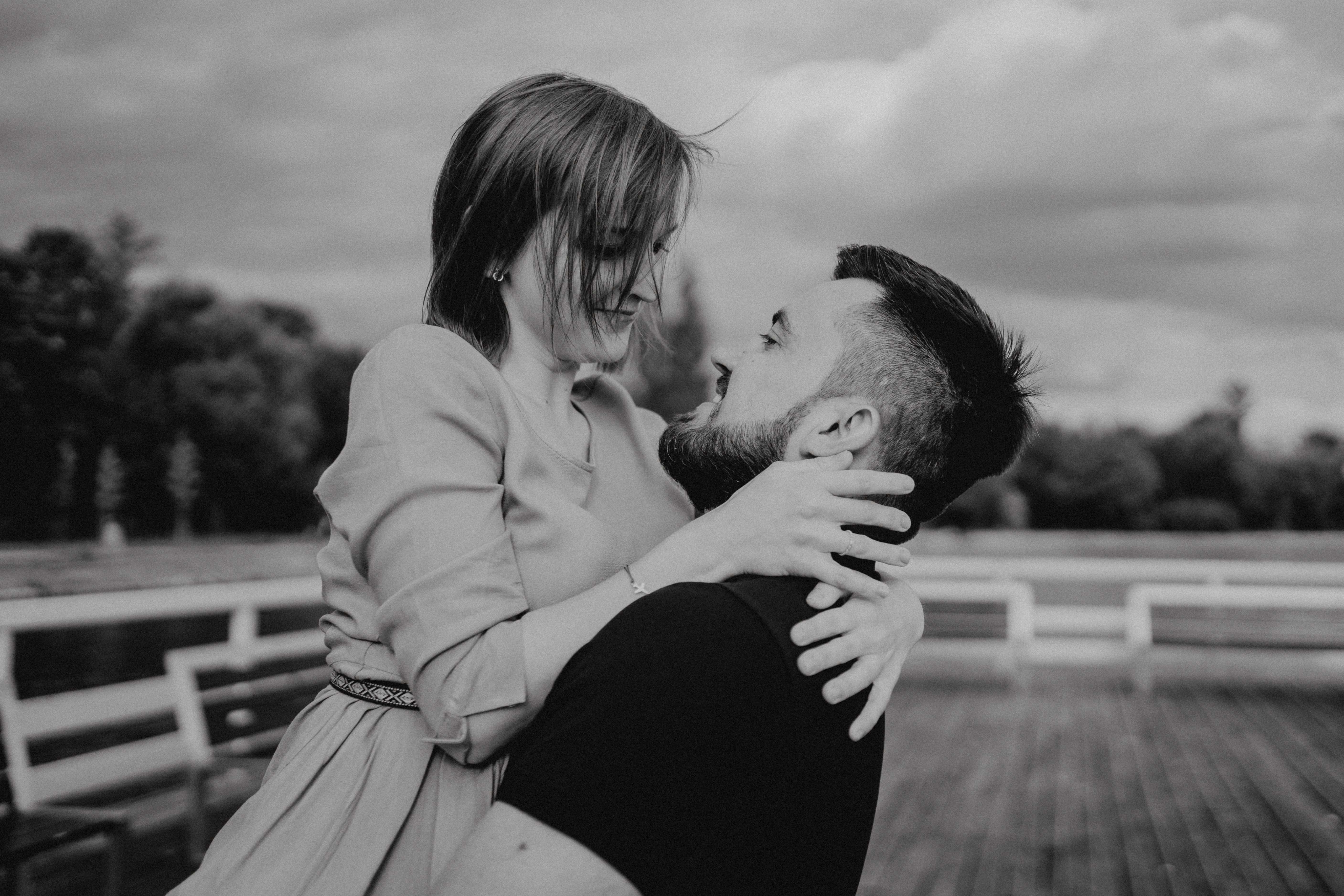 Narzeczeni obejmujący się na tle malowniczego krajobrazu, pełni miłości i spokoju.