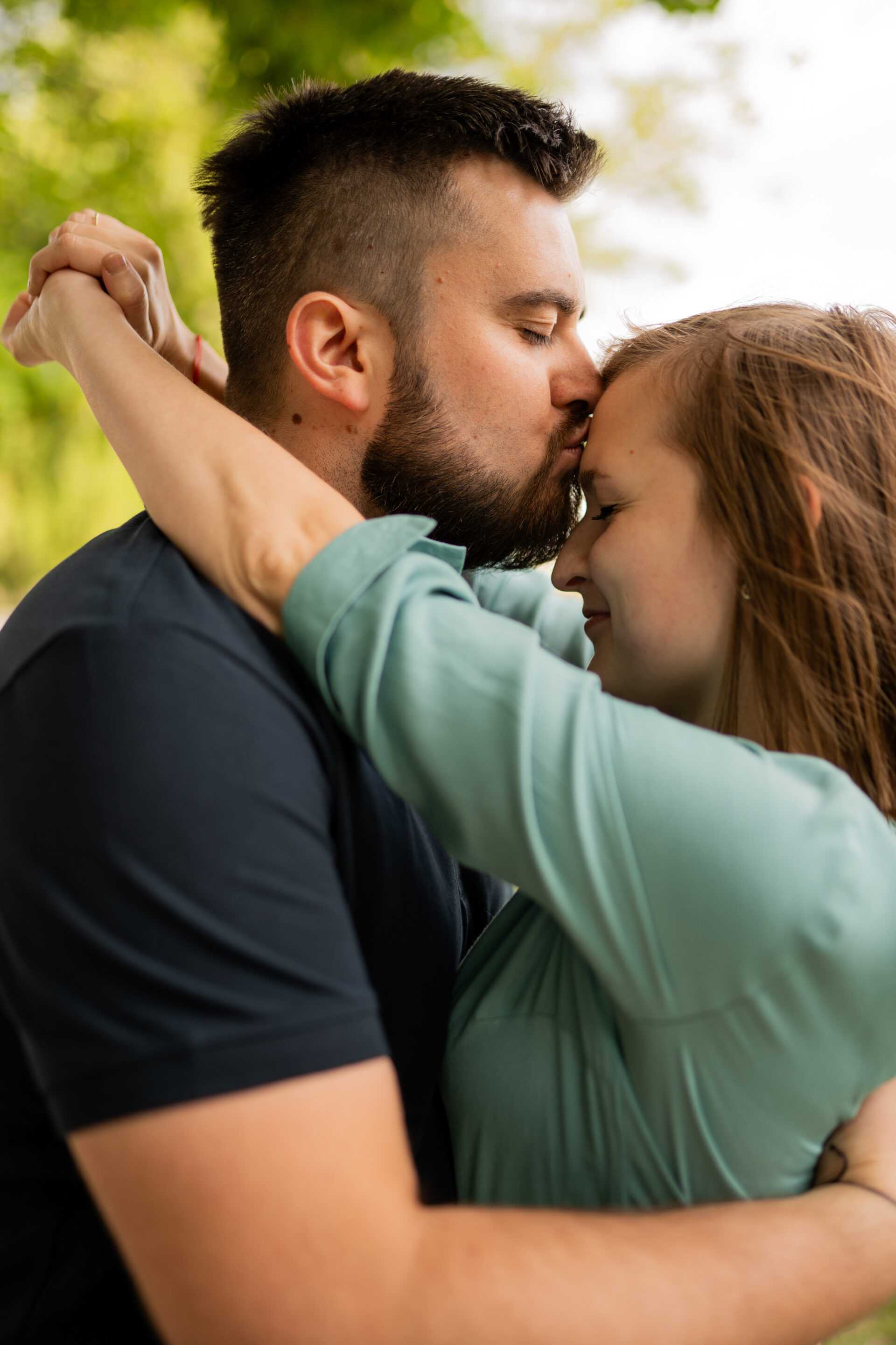 Narzeczeni obejmujący się na tle malowniczego krajobrazu, pełni miłości i spokoju.