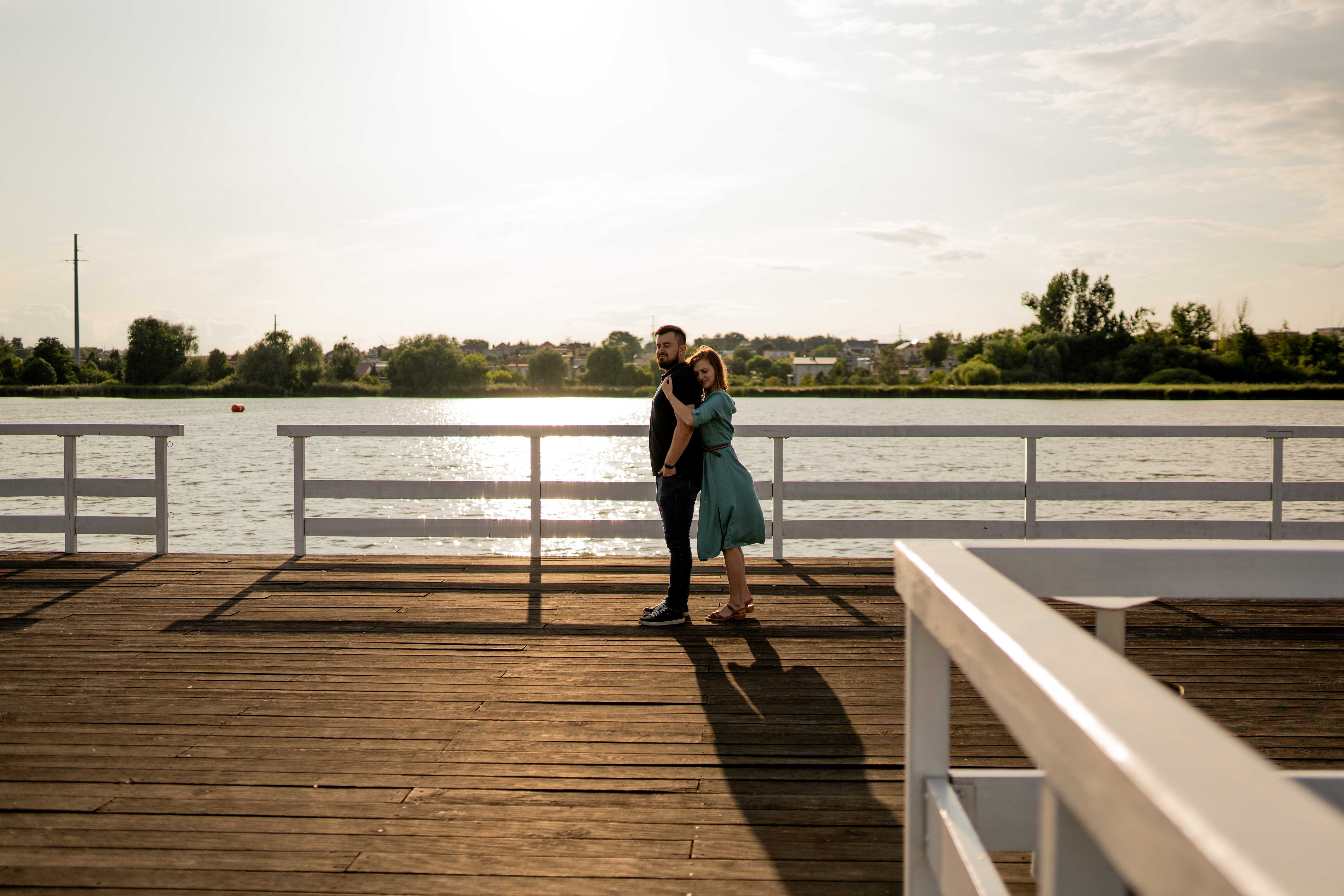 Narzeczeni obejmujący się na tle malowniczego krajobrazu, pełni miłości i spokoju.