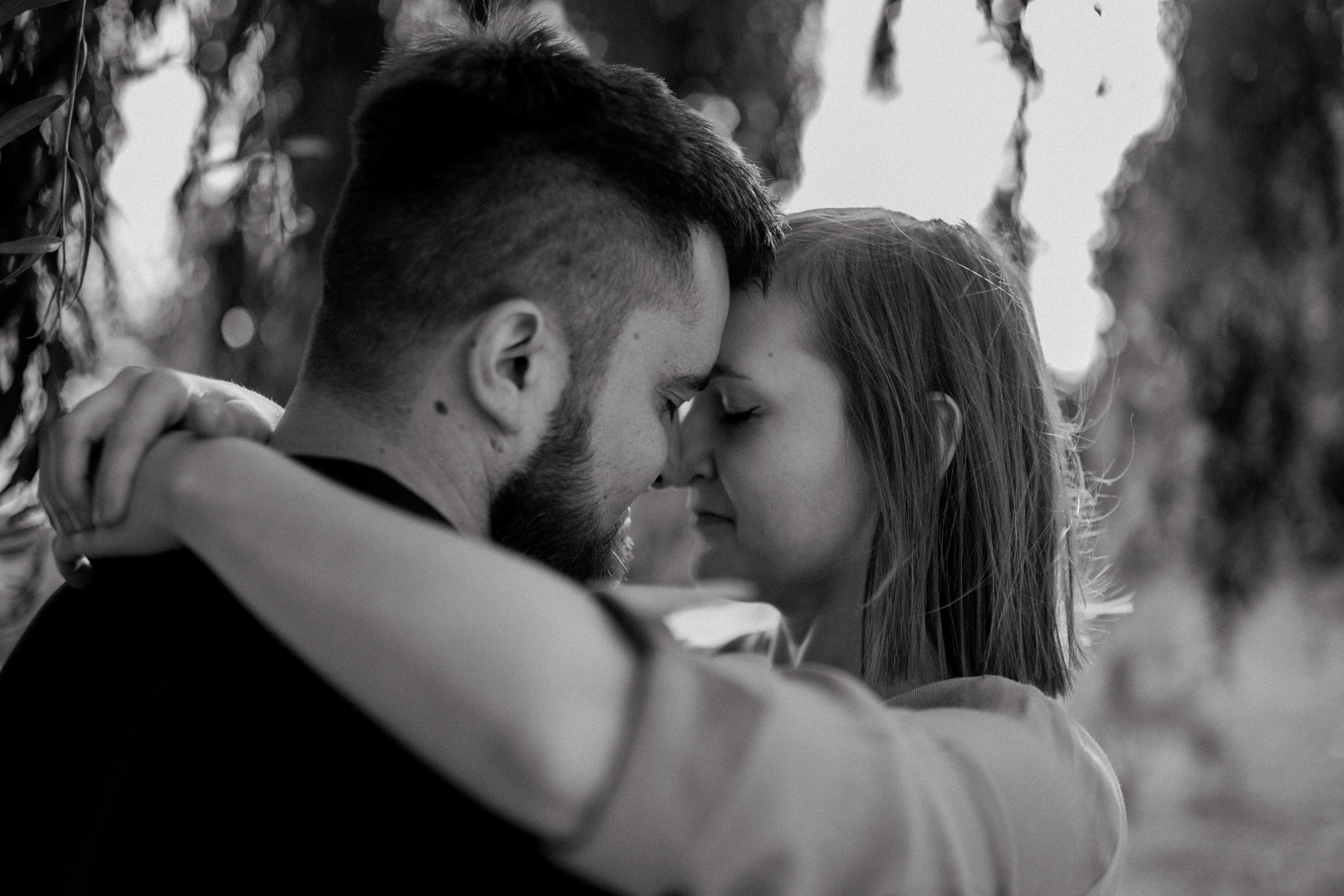 Intymny kadr z czułym spojrzeniem zakochanych, otulonych miękkim światłem.