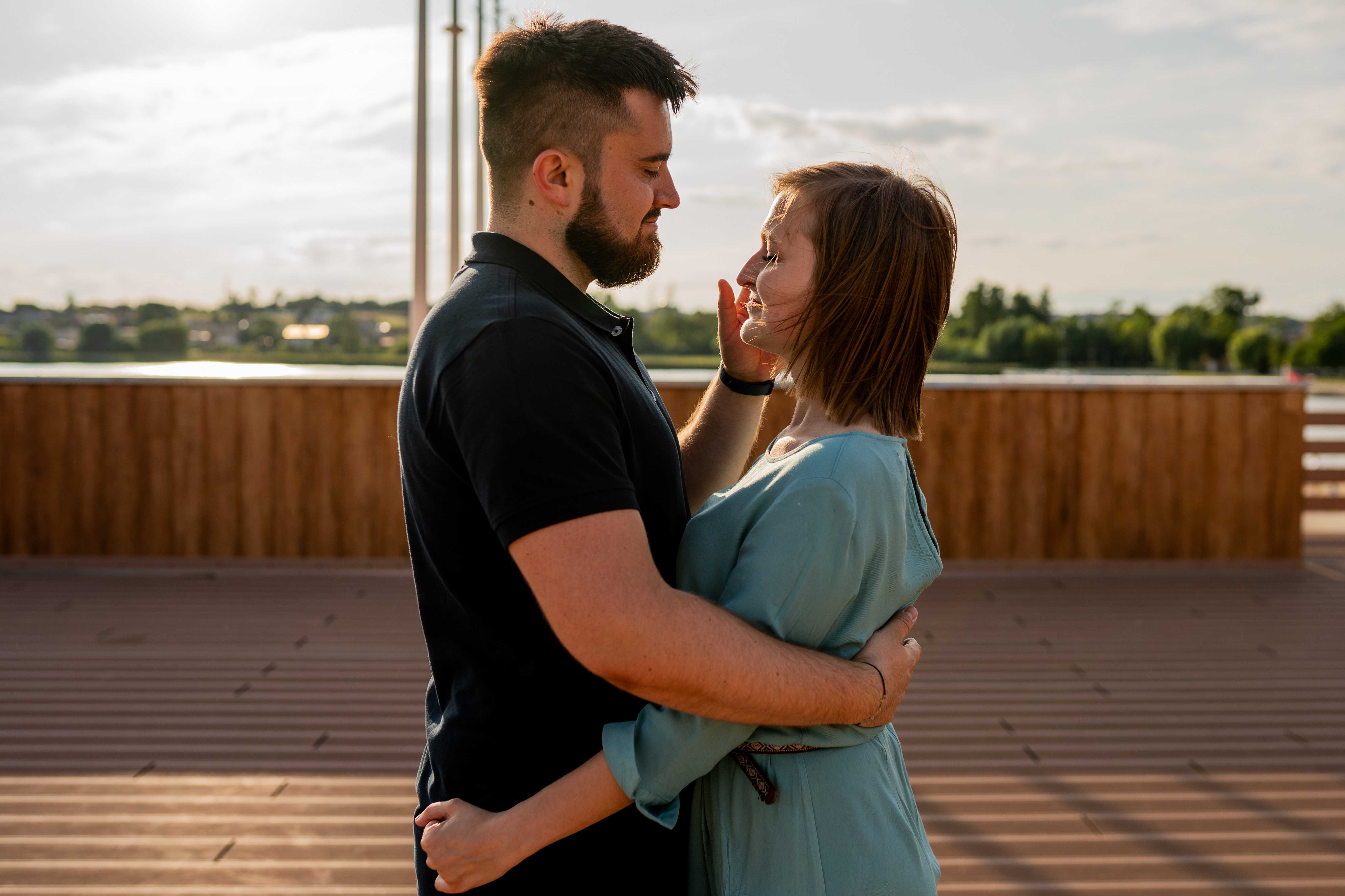 Narzeczeni obejmujący się na tle malowniczego krajobrazu, pełni miłości i spokoju.