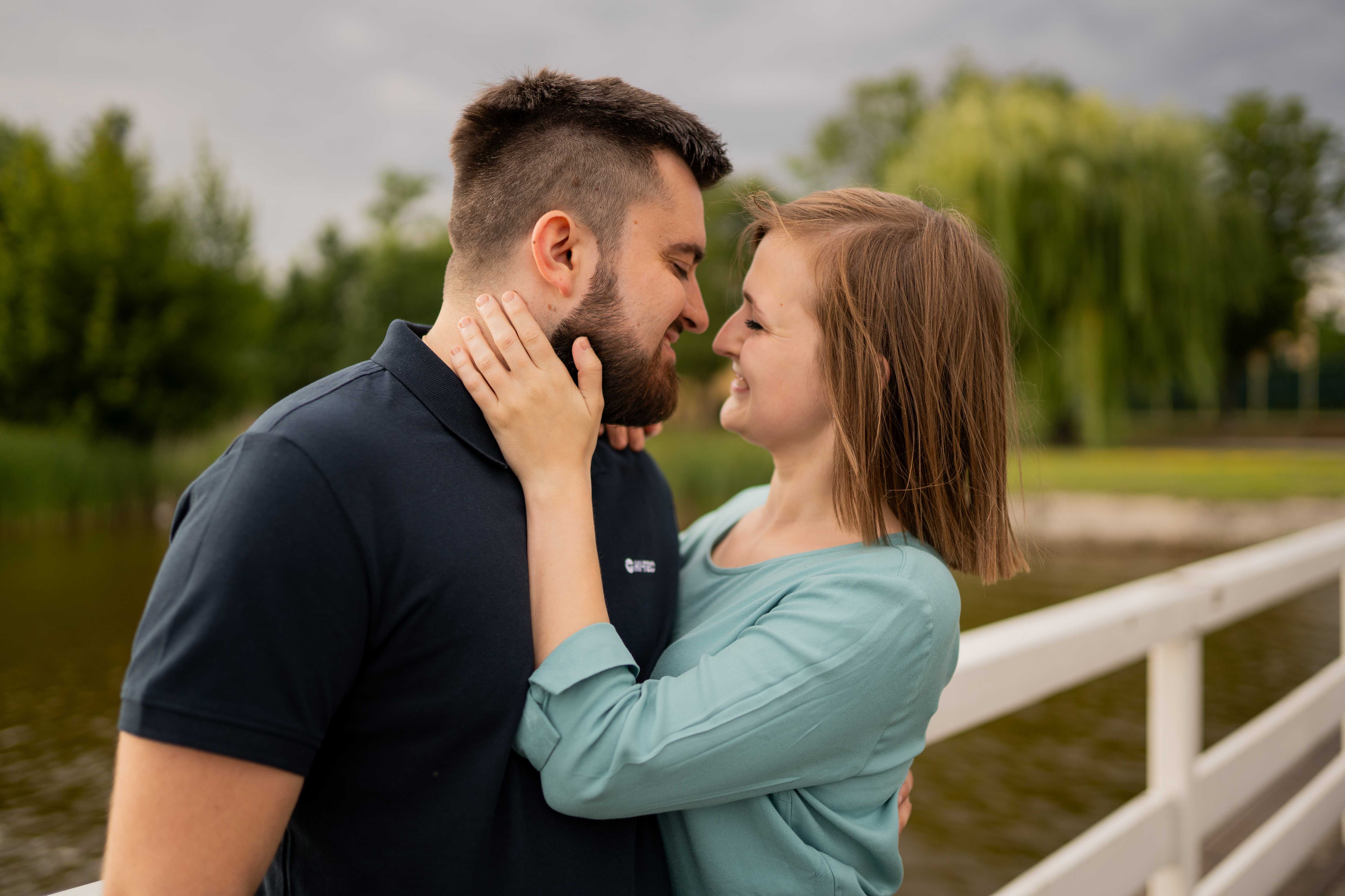Narzeczeni obejmujący się na tle malowniczego krajobrazu, pełni miłości i spokoju.